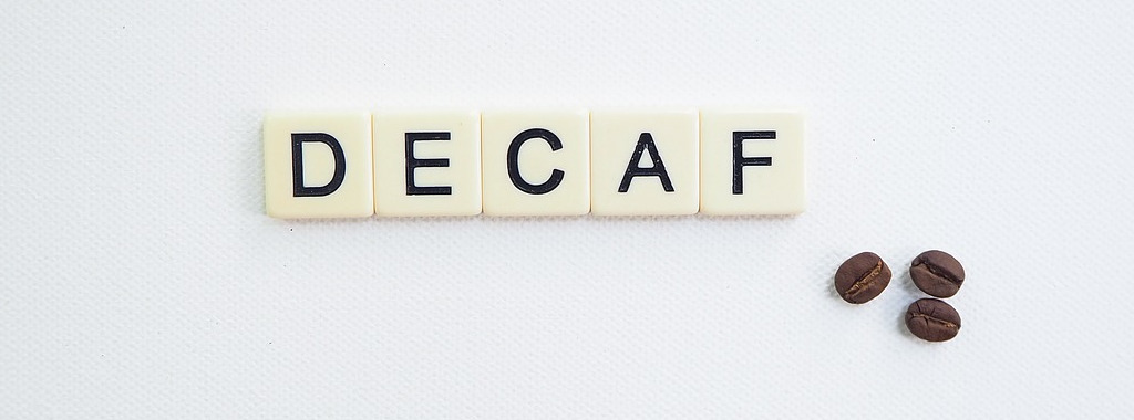 "DECAF" in Buchstaben neben drei Kaffeebohnen.