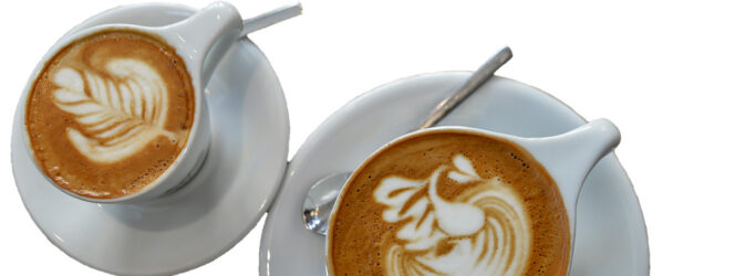 Zwei Tassen Cappuccino auf weißem Hintergrund.