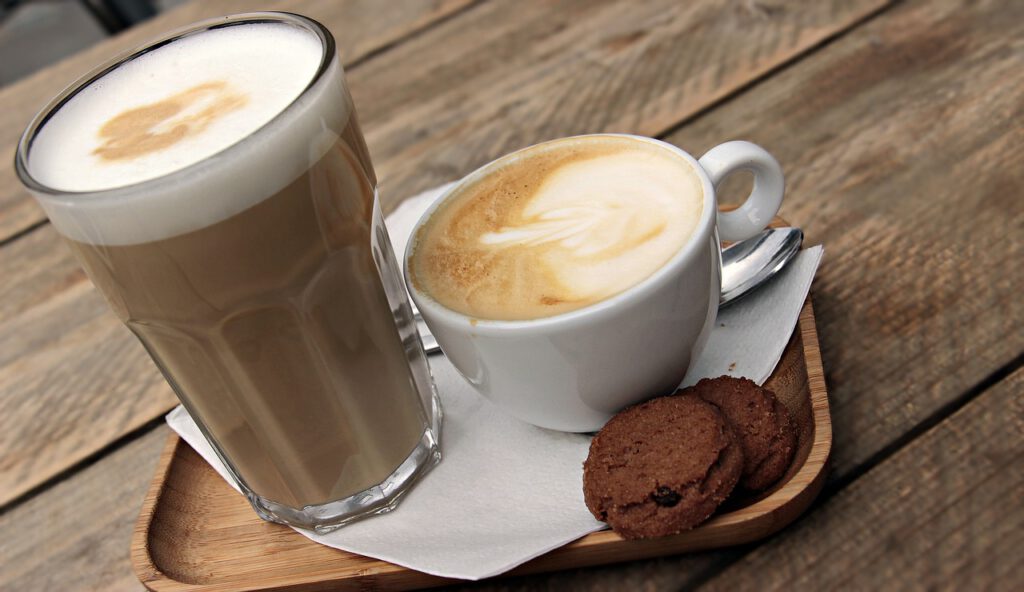 Latte Macchiato und Cappuccino auf einem Serviertablett samt Keksen.